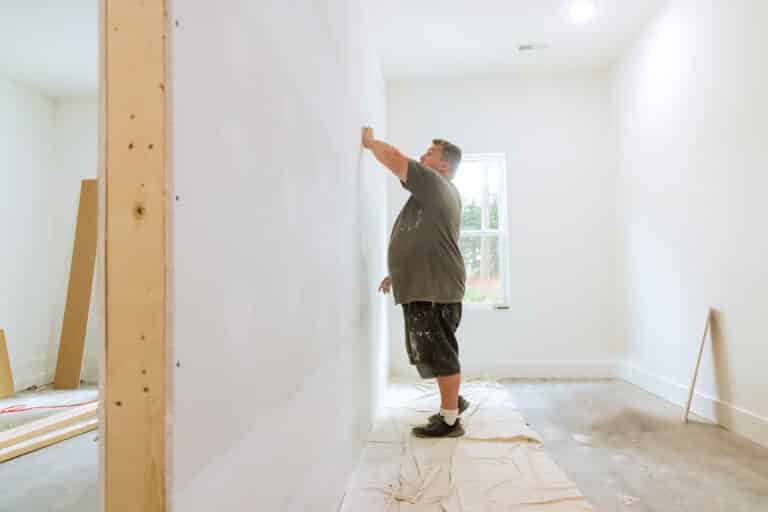 as the work is being carried out on the renovation of the house in the room, a worker is using the sand trowel to sand the drywall mud with