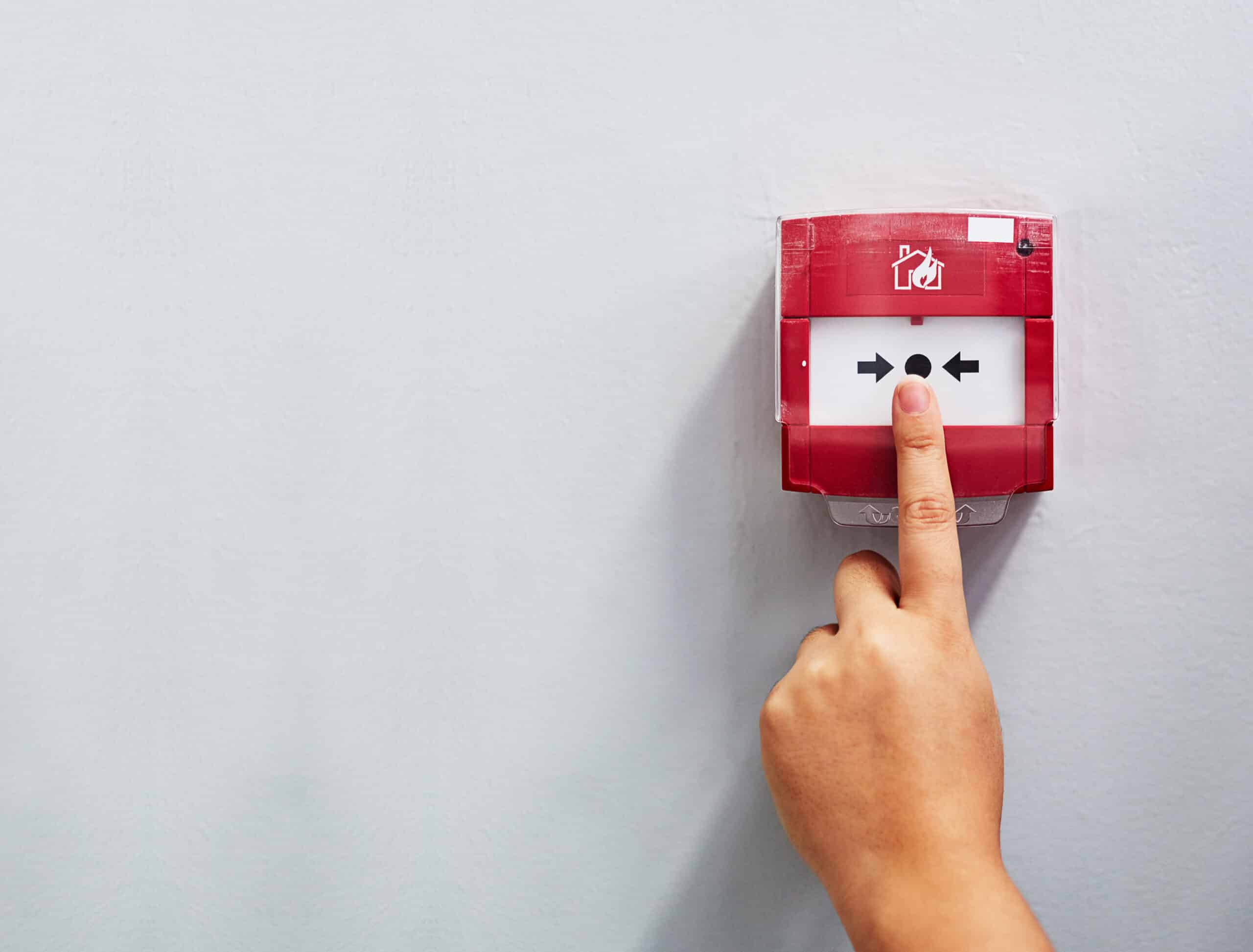 activating the alarm. cropped shot of a person pressing a fire alarm on a wall