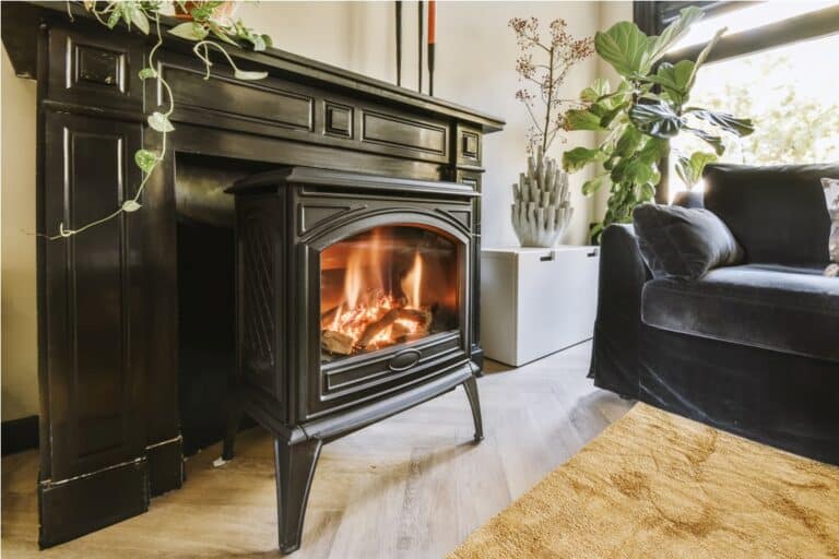 burning wood inside a black fireplace next to a velvet sofa