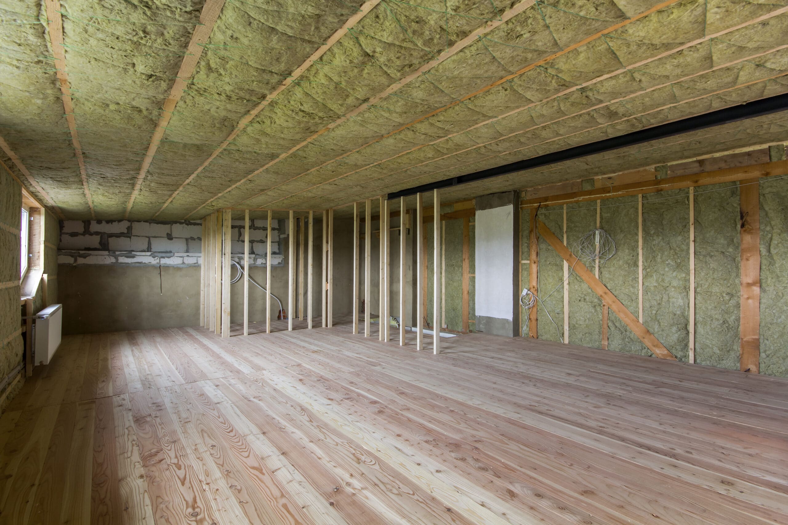 construction and renovation of big spacious empty unfinished attic room with oak floor, walls and ceiling insulated with rock wool and fiber glass for cold barrier and wooden frame for future walls.