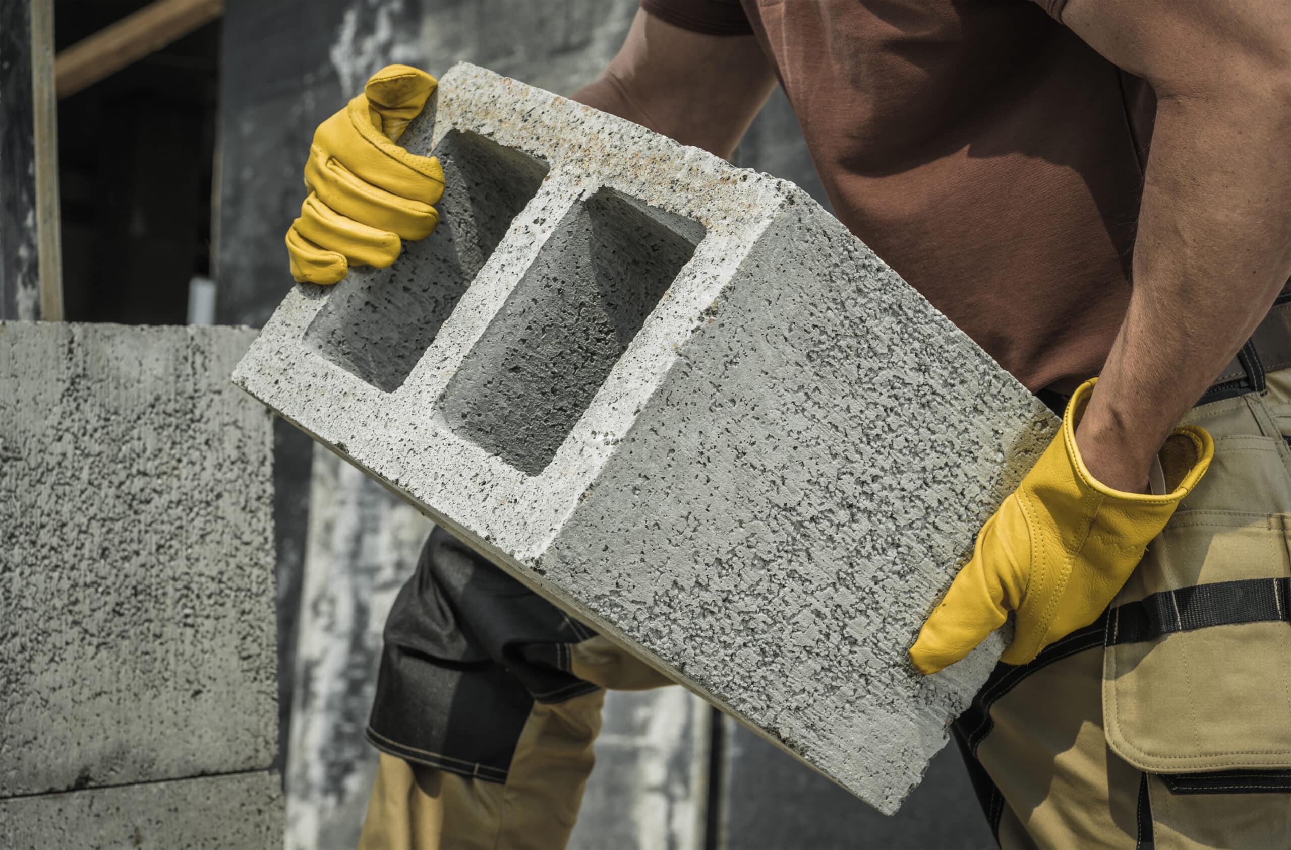 construction worker moving hollow dense concrete blocks