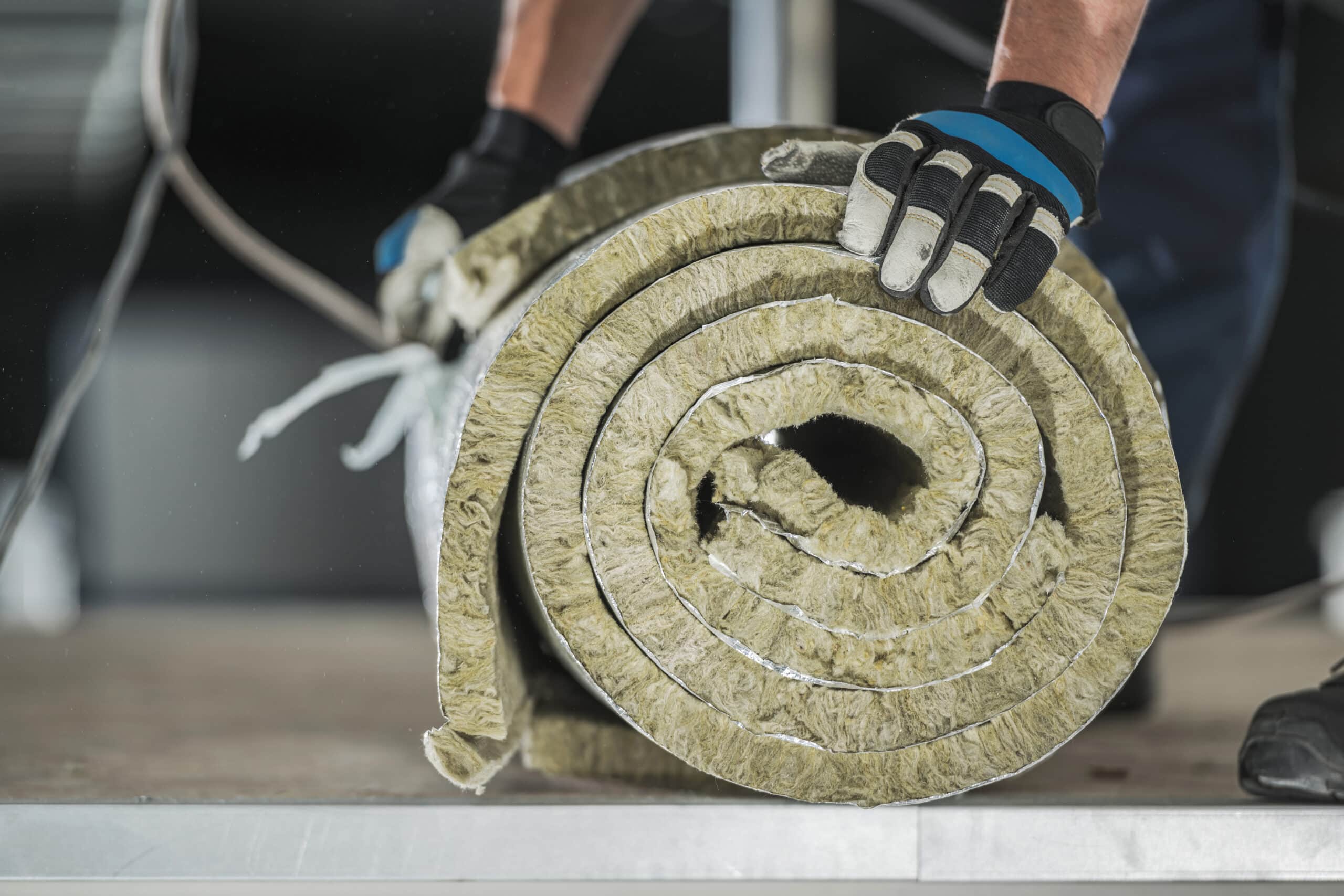 construction worker preparing roll of mineral wool insulation