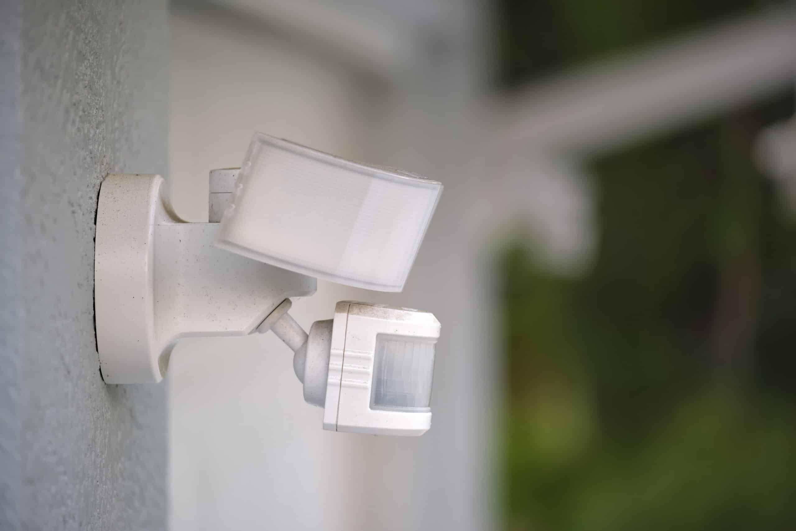 motion sensor with light detector mounted on exterior wall of private house as part of security system