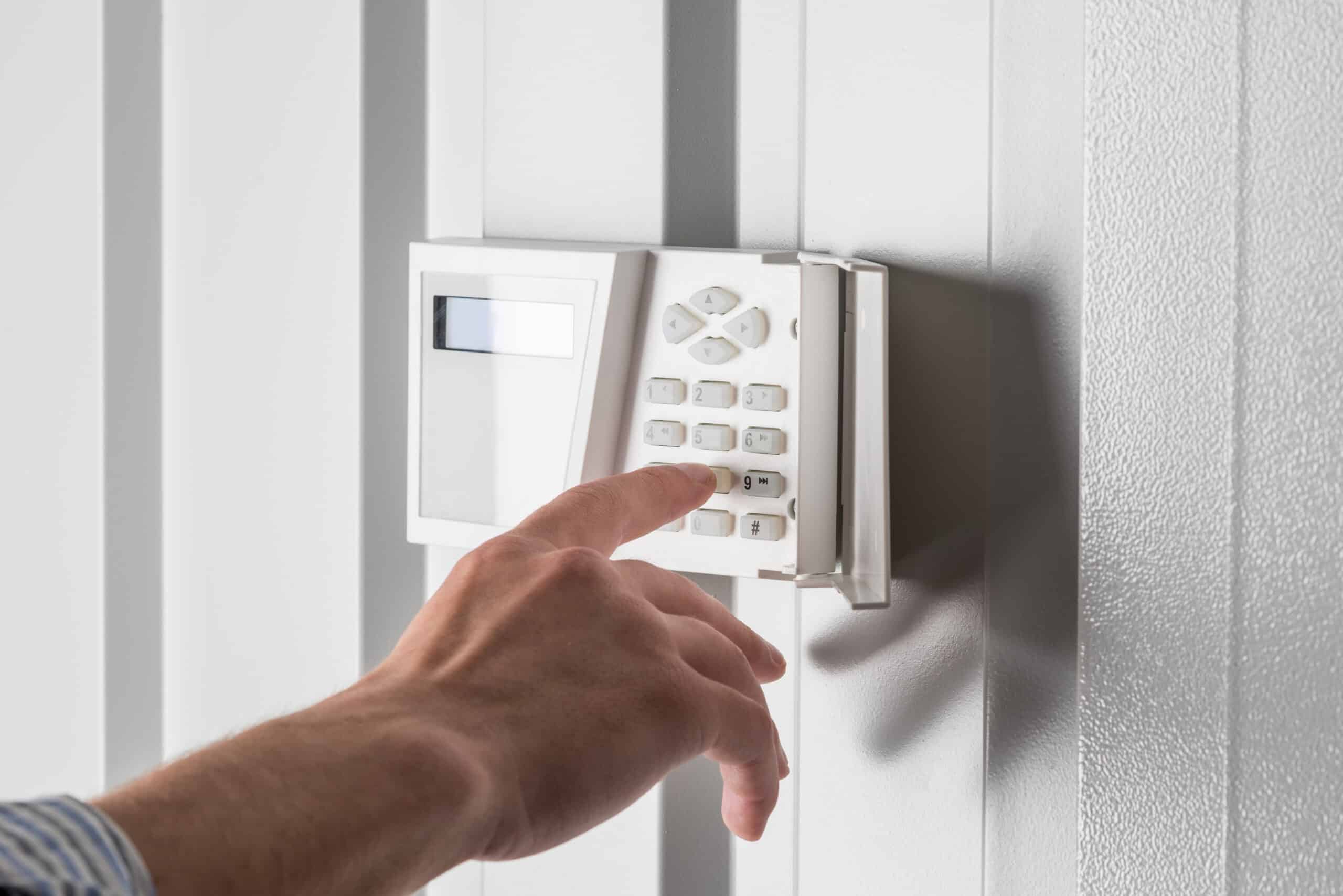 person typing on keypad of home security alarm, security system concept