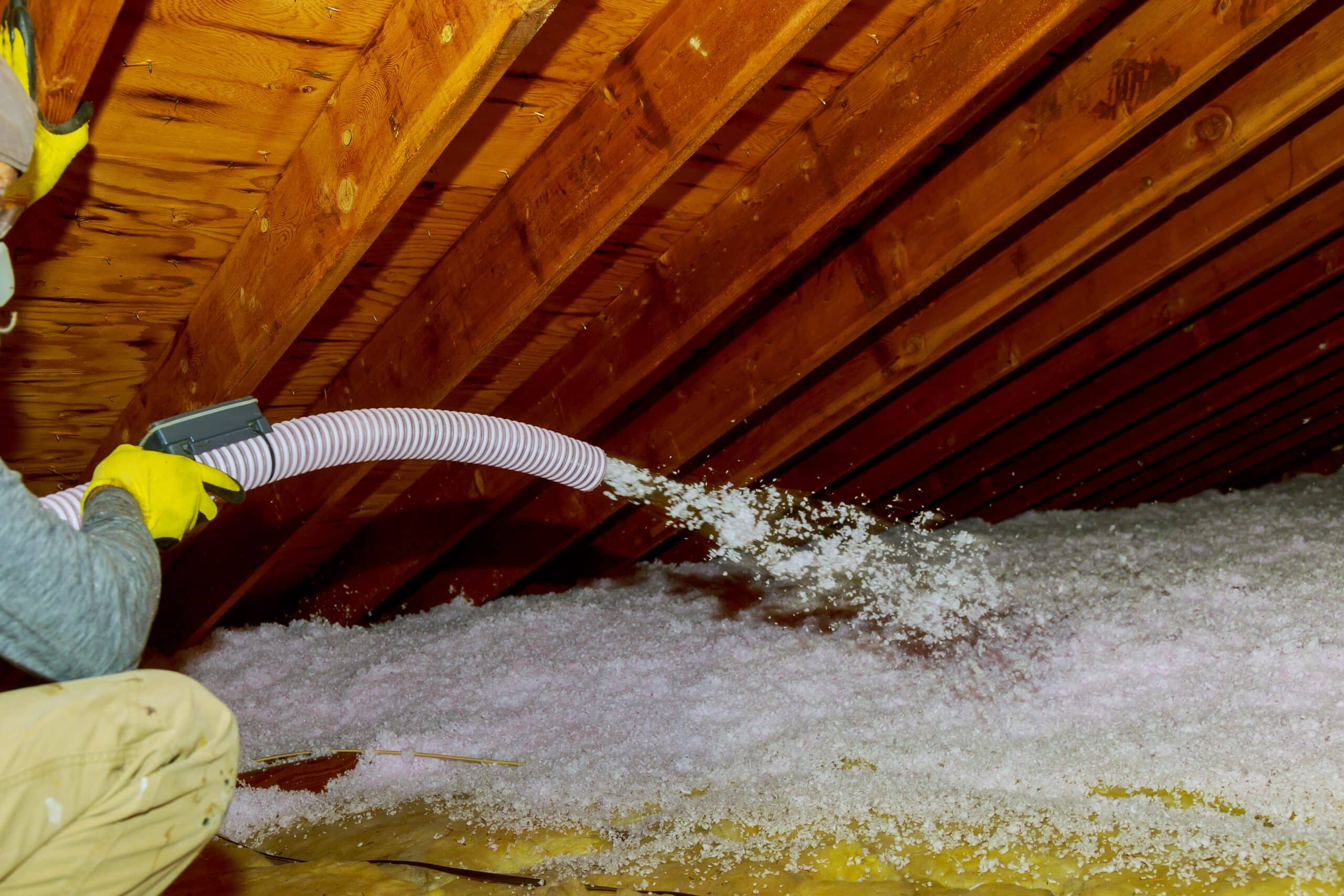 technician spraying blown fiberglass insulation between attic trusses foam insulation construction foam from the gun to the roof