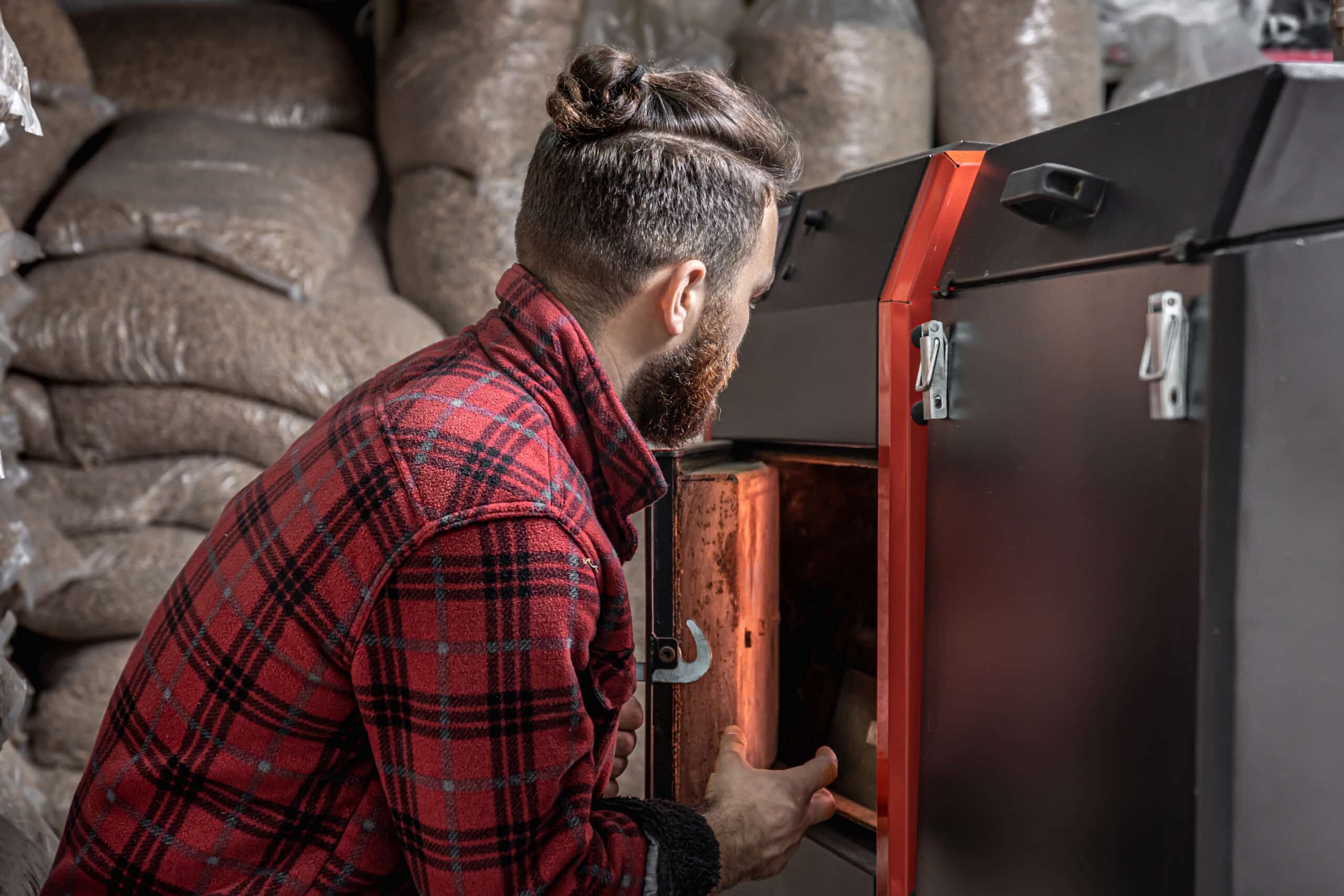 the young man with solid fuel boiler, working with biofuels, economical heating.