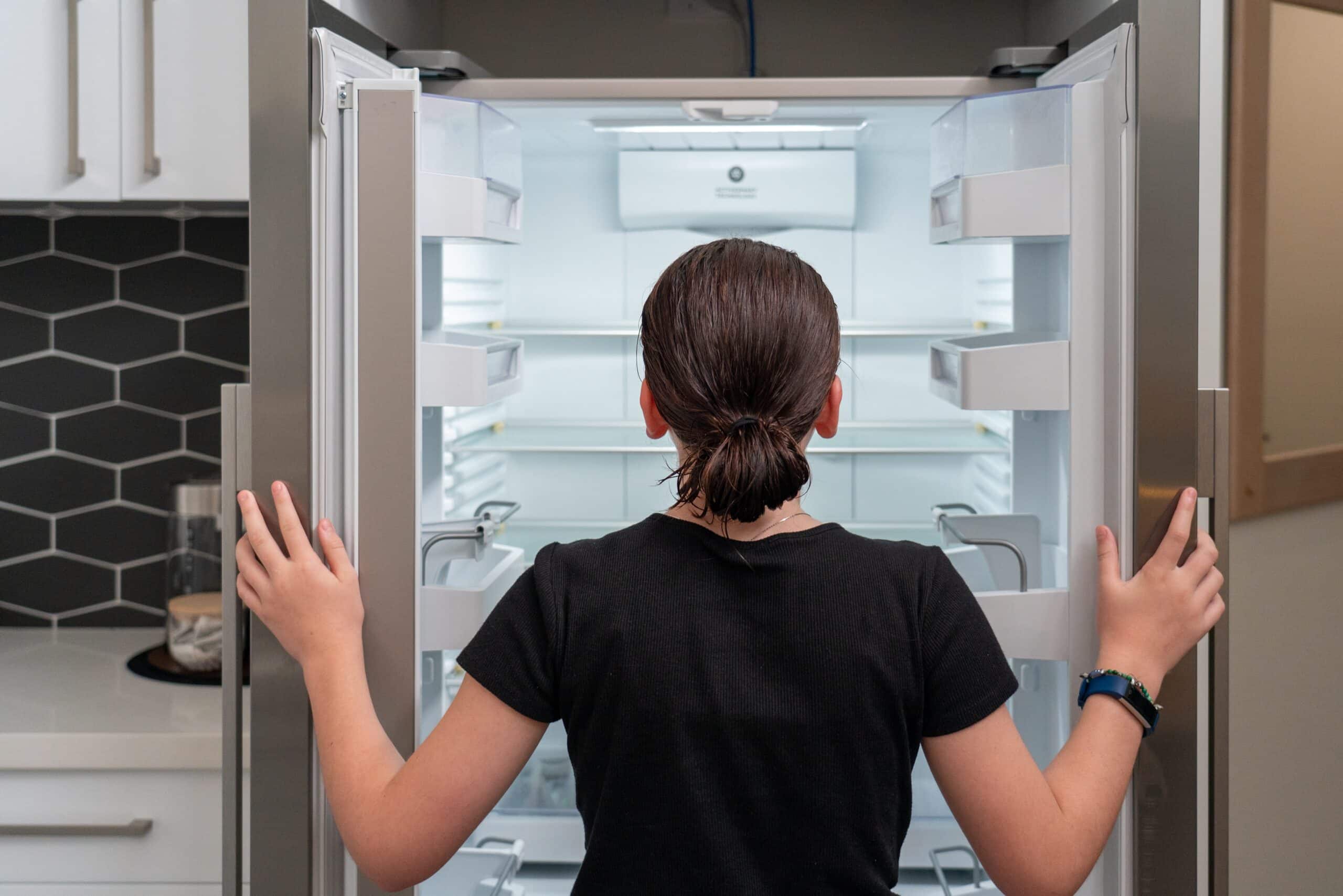 young girl looking into an empty refrigerator frid 2022 10 31 05 59 54 utc