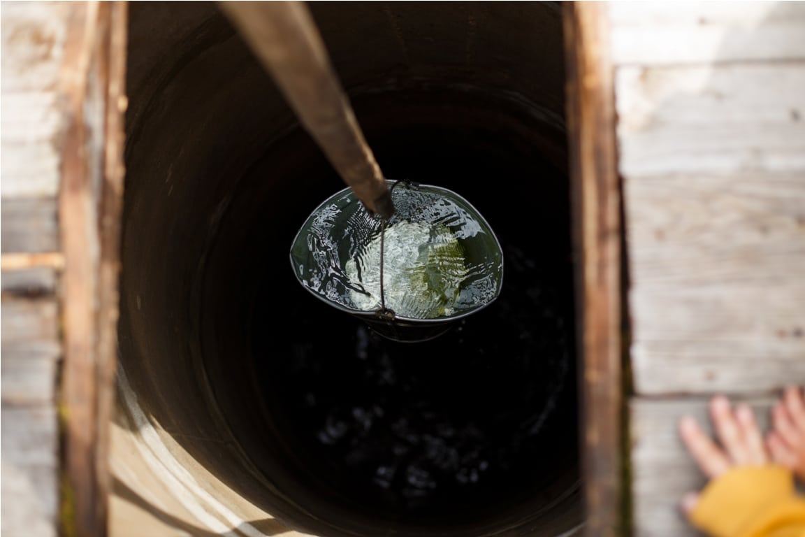 blue bucked inside water well. water well with an old iron bucket