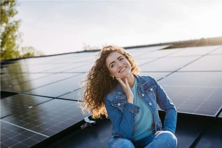 portrait of young woman, owner on roof with solar panels.