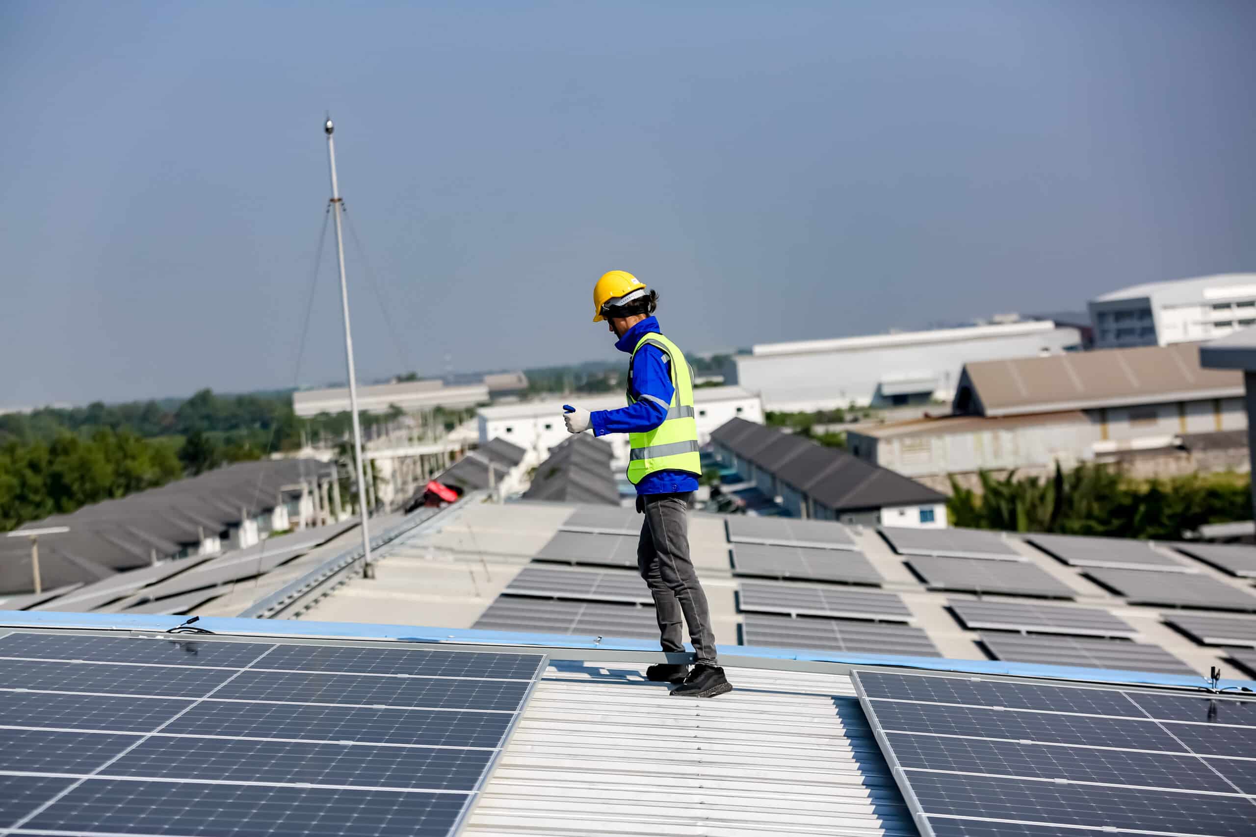 solar panel installer installing solar panels on roof of warehouse