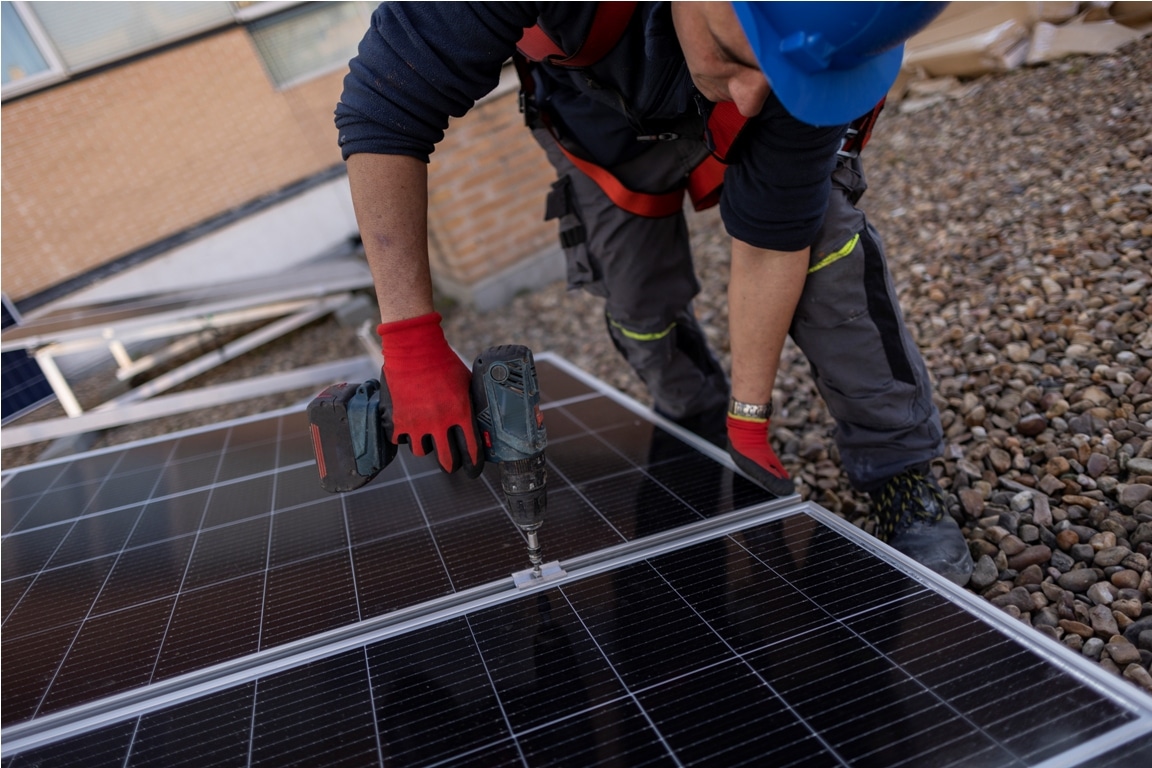 worker installing a solar panel on the roof