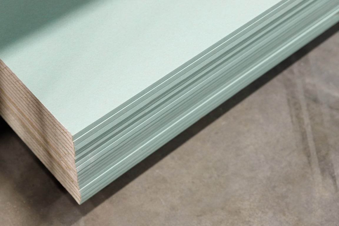 a high angle closeup of green plasterboard on a grey surface