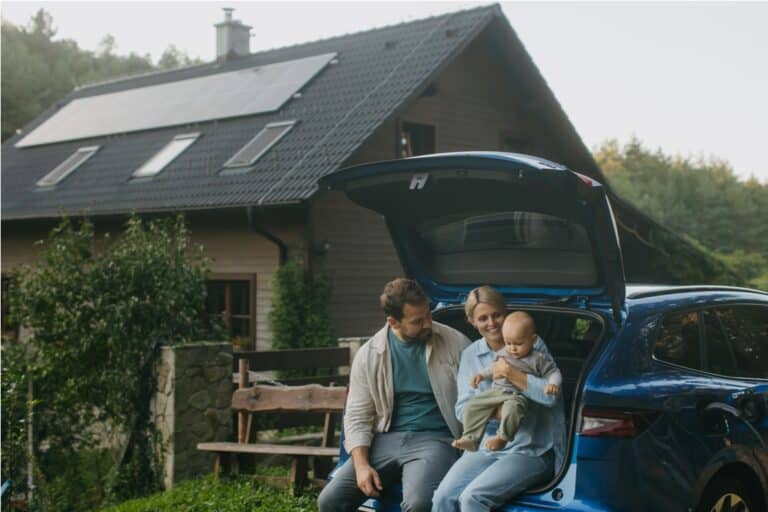 family sitting in trunk of electric car with hous 2023 10 31 18 33 05 utc