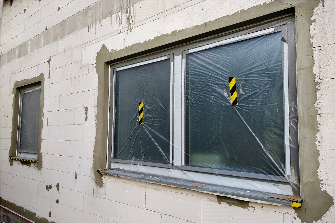 windows of a house under construction covered with protective plastic film.